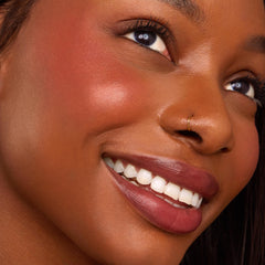 Blush nβ Pout ColourPop Cheek & Lip Set adding a warm rosy flush and berry-mauve satin lip to a smiling model in a close-up beauty shot, highlighting smooth skin, defined lashes, and a small gold nose ring under soft studio lighting.