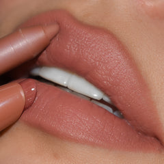 ColourPop Cookie Lippie Stix gliding onto lips, paired with a matching nude liner to define the cupidβs bow, showcasing a creamy warm beige-nude color in a tight close-up beauty shot.