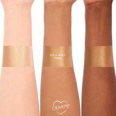ColourPop SOL Glow Oil It’s a Wolf Thing swatched in wide bands across three arms with light, medium, and deep skin tones, revealing a warm golden shimmer and glossy finish; ColourPop heart logo at the bottom.