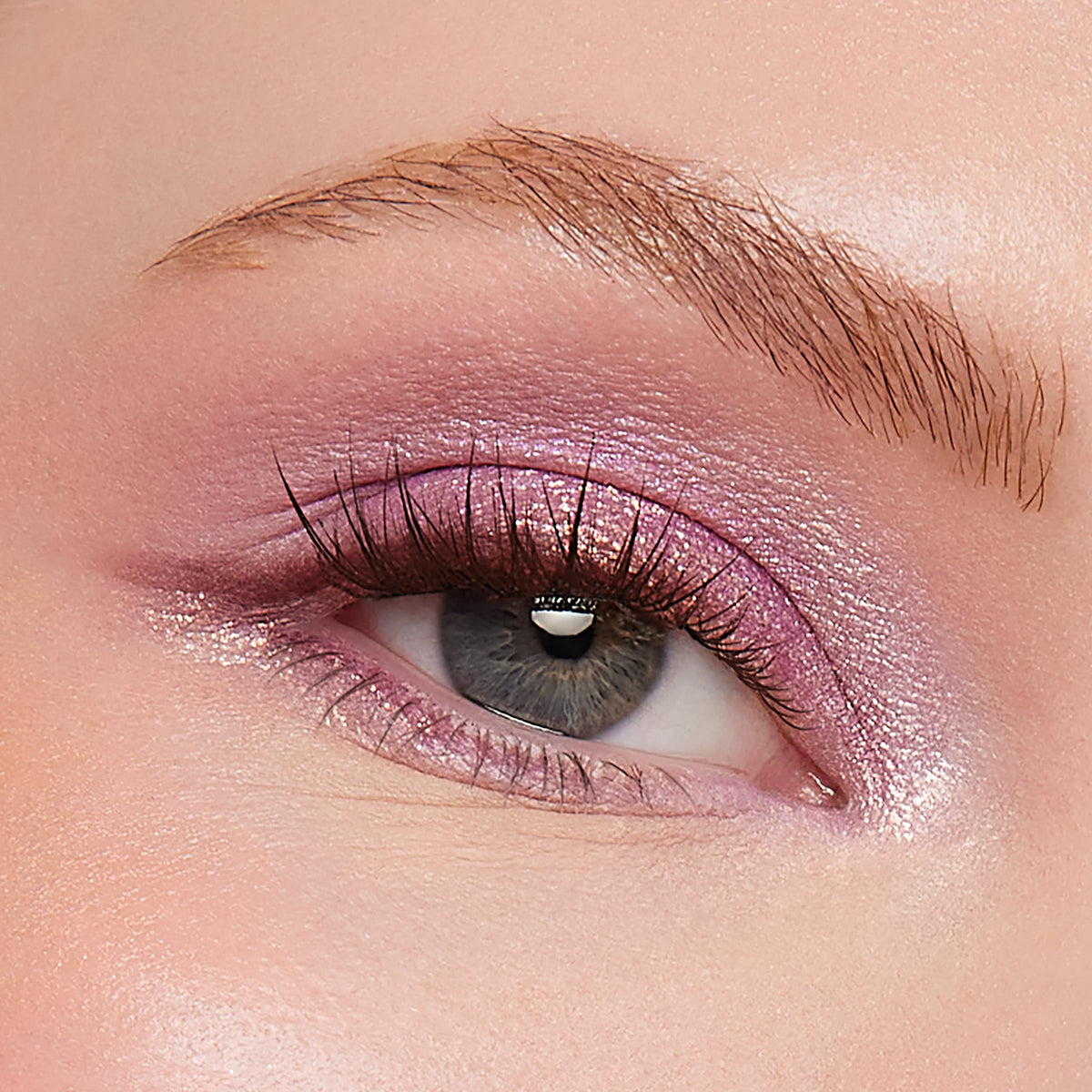 Shimmery pink-lilac eyeshadow sweeps across the upper lid and inner corner on a close-up gray eye, catching light and defining natural lashes and brow, showcasing Best Day Ever, a ColourPop Shadow Palette.
