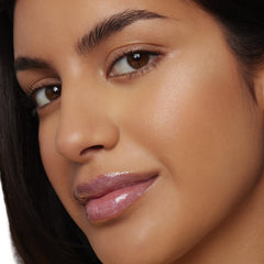 ColourPop Liquid Highlighter Mother Gothel illuminating a model’s cheekbone and brow bone with a dewy, soft-focus glow in a studio close-up, showcasing smooth skin and natural makeup for a radiant, lit-from-within finish.
