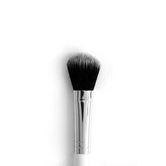ColourPop Small Fluff Brush makeup brush blending and packing shadow, featuring dense black-to-gray fluffy bristles with a domed edge, a polished silver ferrule, and a white handle, shown upright on a clean white background.